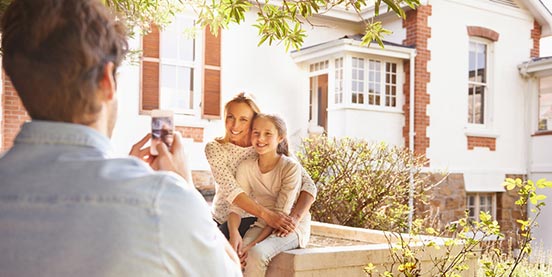 a father taking a family photo in front of a home