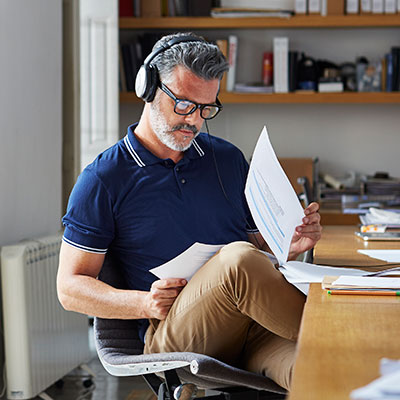 man reading papers at desk with headphones on