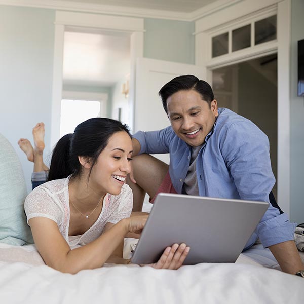 Couple using digital tablet on bed